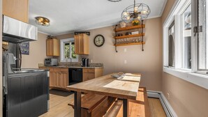 Eine Küche mit Holzausstattung, einem Esstisch und einem eingebauten Backofen.
