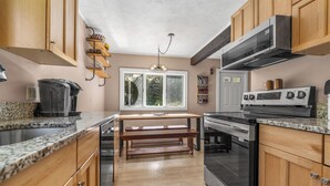 Eine moderne Küche mit Holzschränken, Granit Arbeitsplatten, einem Edelstahlherd und einem eingebauten Backofen.
