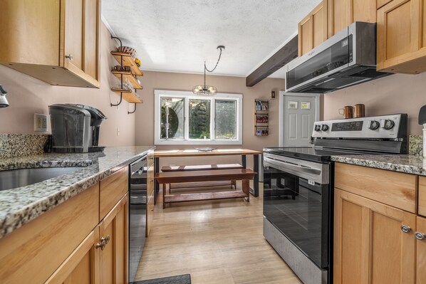 A modern kitchen with wooden cabinets, granite countertops, a stainless steel range, and a built-in oven.