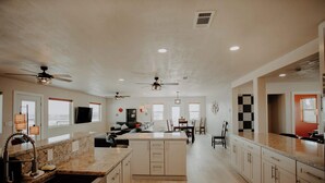 A spacious kitchen with a central island, built-in appliances, and a dining area with chairs and a table. - Casa Abuelo Loco, Terlingua's Premier Vacation Rental (Terlingua)