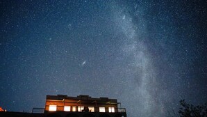 A building with multiple windows and a balcony, under a starry night sky. - Casa Abuelo Loco, Terlingua's Premier Vacation Rental (Terlingua)