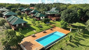Un resort con varias cabañas, una piscina y abundante vegetación.