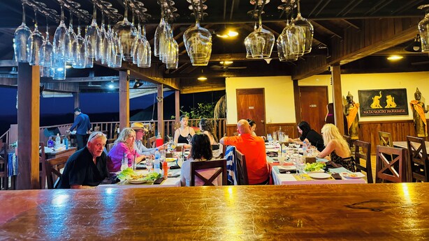 Un restaurante con varias mesas, lámparas colgantes y un letrero con figuras de animales.
