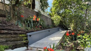 A staircase with a concrete handrail, surrounded by lush greenery and flowering plants. - A private studio on Hobson Bay in historic Parnell. Central Auckland. (Auckland)