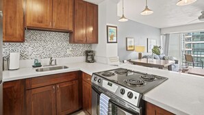 Une cuisine moderne avec des meubles en bois, une cuisinière en acier inoxydable et une grande fenêtre donnant sur un balcon.