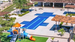 A swimming pool with a blue deck, a children's play area, and a covered patio area. - Family-Friendly 3BR | Pool | Near Tamarindo (Villareal)