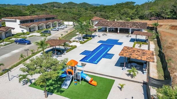 A residential area with multiple houses, a playground, and a swimming pool. - Family-Friendly 3BR | Pool | Near Tamarindo (Villareal)
