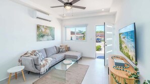 A modern living room with a grey sectional sofa, a glass coffee table, and a ceiling fan. - Family-Friendly 3BR | Pool | Near Tamarindo (Villareal)