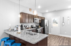 Eine moderne Küche mit Granit Arbeitsplatten, Edelstahlgeräten und Holzschränken.