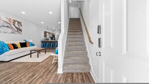 A modern living room with a staircase leading to a kitchen area.
