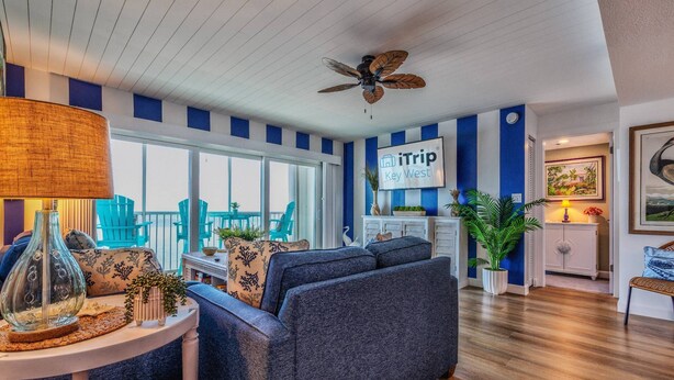 Un salon moderne aux couleurs bleu et blanc, doté d’un ventilateur de plafond et d’une enseigne indiquant « iTrip Key West ».