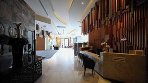 A modern hotel lobby with a reception desk, seating area, and decorative elements like wall art and plants. - Specious Luxury 2 bedrooms Apt. (Chiang Mai)
