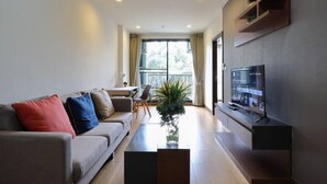 A modern living room with a sofa, coffee table, TV, and a balcony view. - Specious Luxury 2 bedrooms Apt. (Chiang Mai)