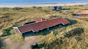 A modern house with a red-tiled roof, situated on a grassy hill overlooking a beach. - "Jaana" - 10m from the sea by Interhome (Blåvand)