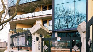 En moderne bygning med en glasfacade, en lukket indgang og et træ i forgrunden.