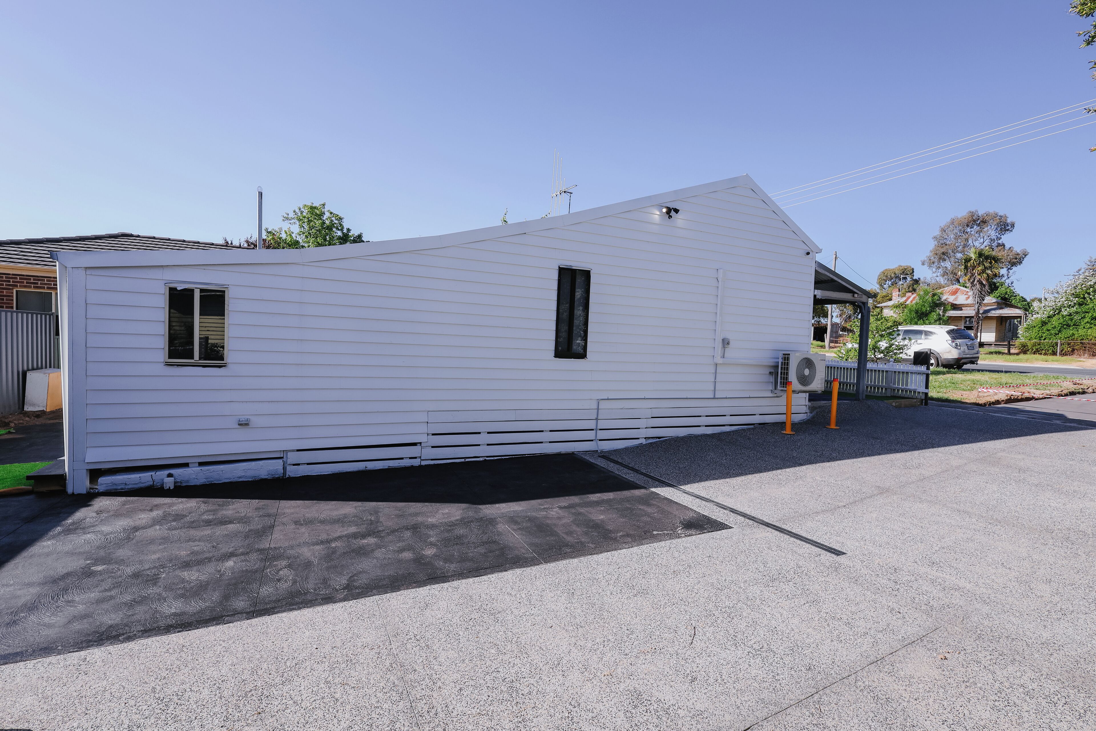 Ein weißer Wohnwagen mit Satteldach, einer kleinen Veranda und einer Auffahrt.