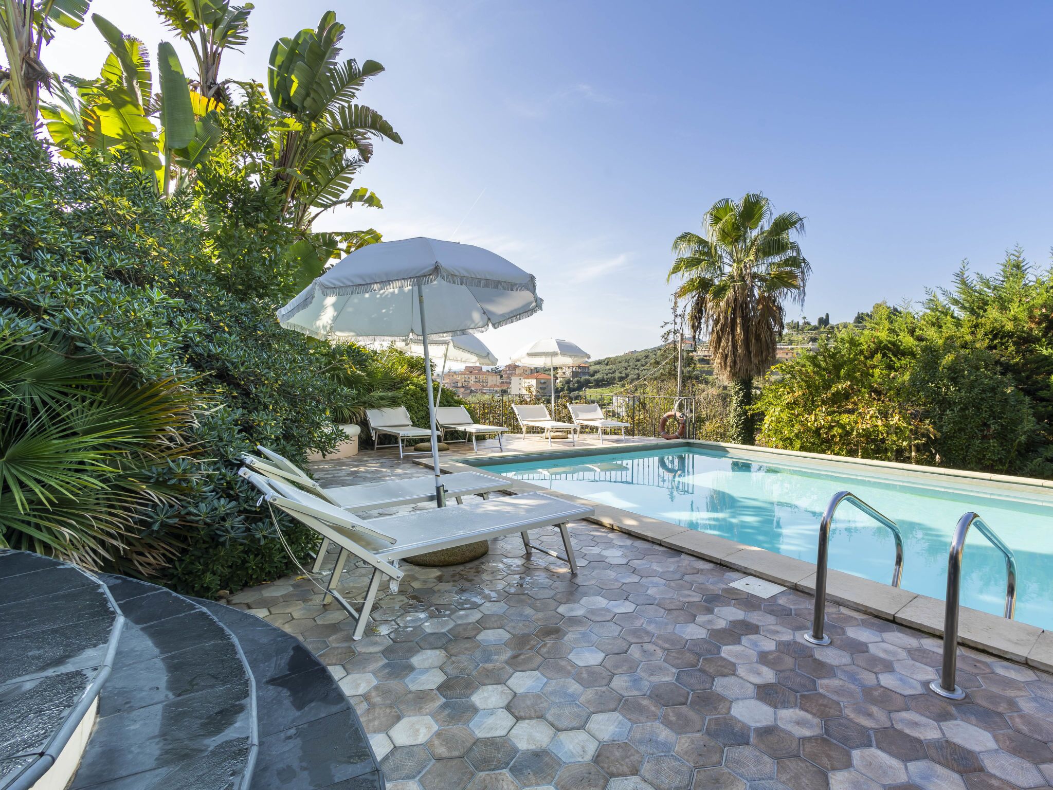 A pool area with hexagonal tiles, lounge chairs, and umbrellas.