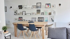 A modern dining area with a wooden table and chairs, surrounded by white walls adorned with framed artwork. - Porthtowan Coastal Escape with minutes away from the Beach (Truro)