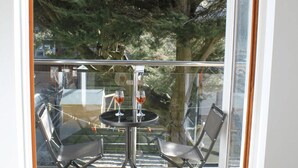 A balcony with a glass door, two chairs, a small table, and two glasses of red wine. - Porthtowan Coastal Escape with minutes away from the Beach (Truro)