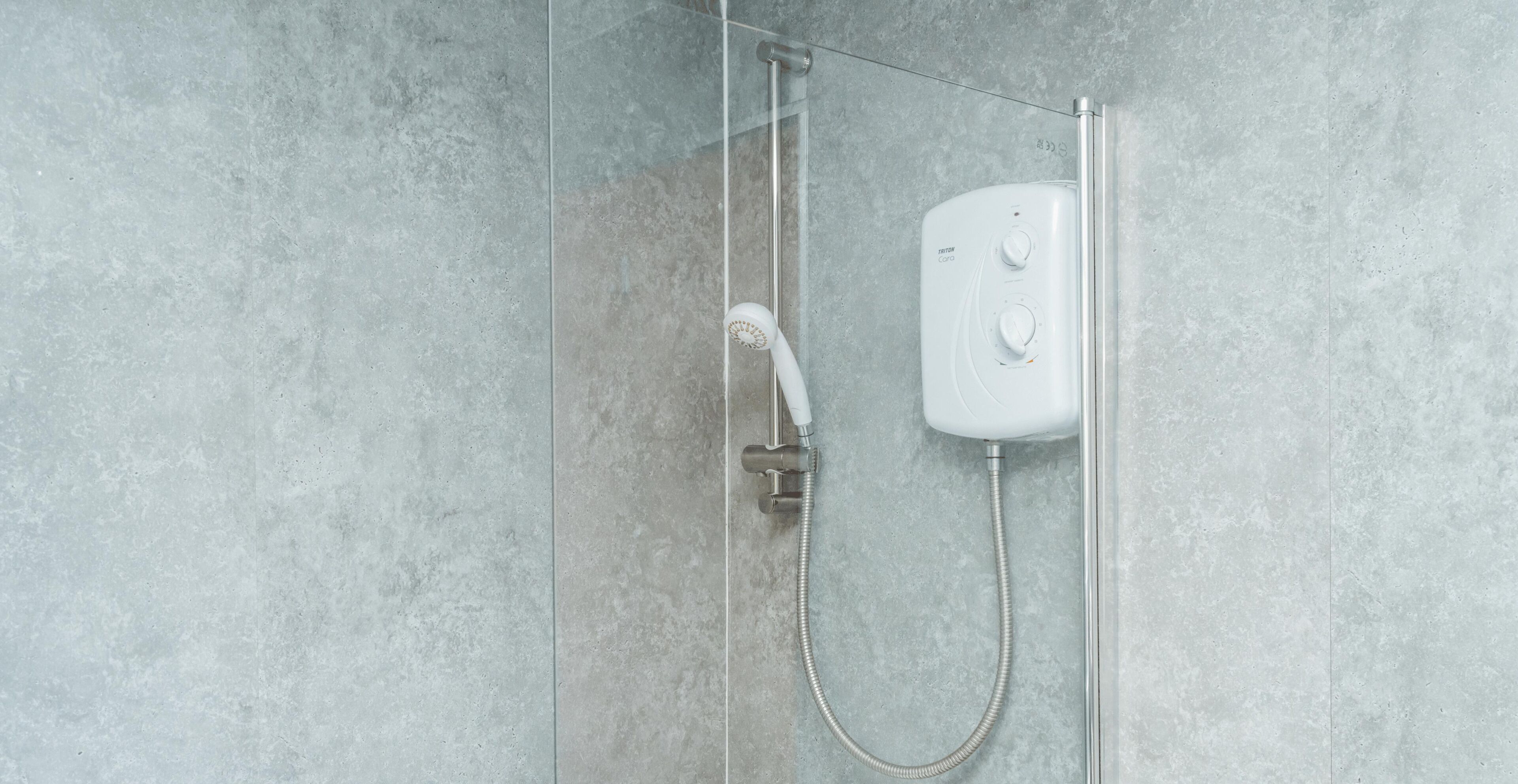 A shower with a handheld showerhead and a wall-mounted control panel.