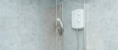 A shower with a handheld showerhead and a wall-mounted control panel.