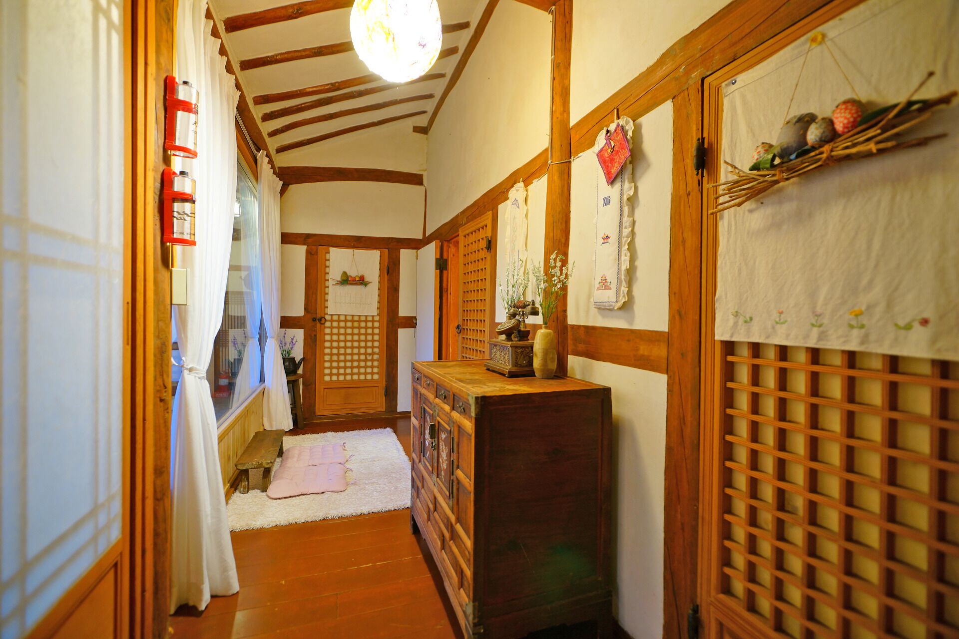 Un interior japonés tradicional con vigas de madera, suelo de tatami, un aparador de madera y una puerta corrediza shoji.