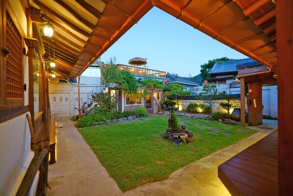 A traditional Japanese-style building with a wooden exterior, a thatched-roof structure, and a well-maintained garden with a koi pond. - sky-kiwa (Jeonju)