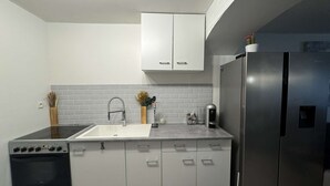 Eine moderne Küche mit weißen Schränken, einem Edelstahlkühlschrank und einem eingebauten Backofen.