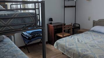 Une chambre de dortoir équipée de lits superposés, d’un bureau, d’une chaise et d’un portant à vêtements.