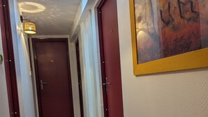 A hallway with wooden flooring, red doors, and a skylight. - AUBERGE DES PINS (Aubenas)