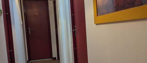 A hallway with wooden flooring, red doors, and a skylight.