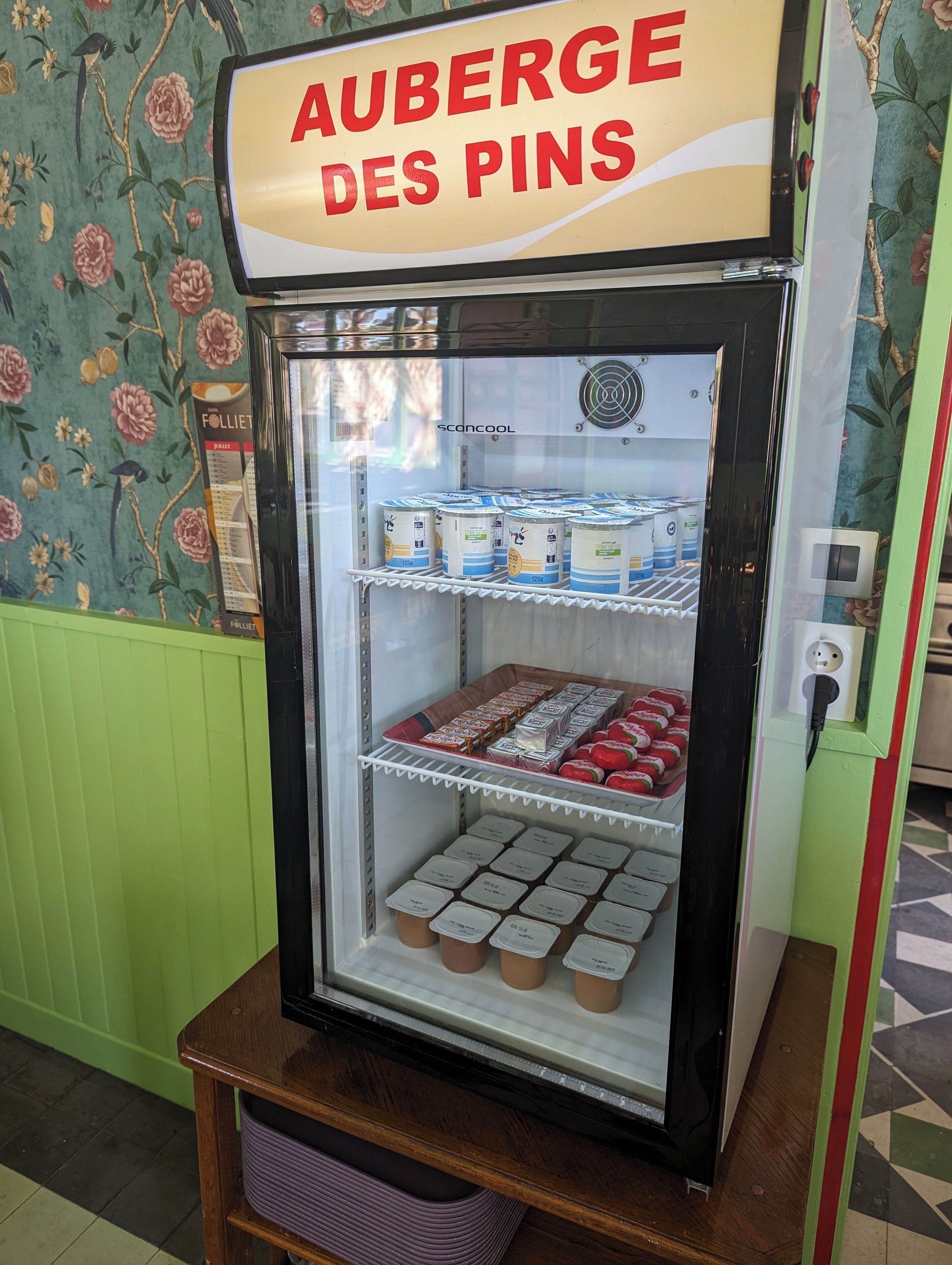 A vending machine labeled "AUBERGE DES PINS" with various packaged goods and beverages inside.