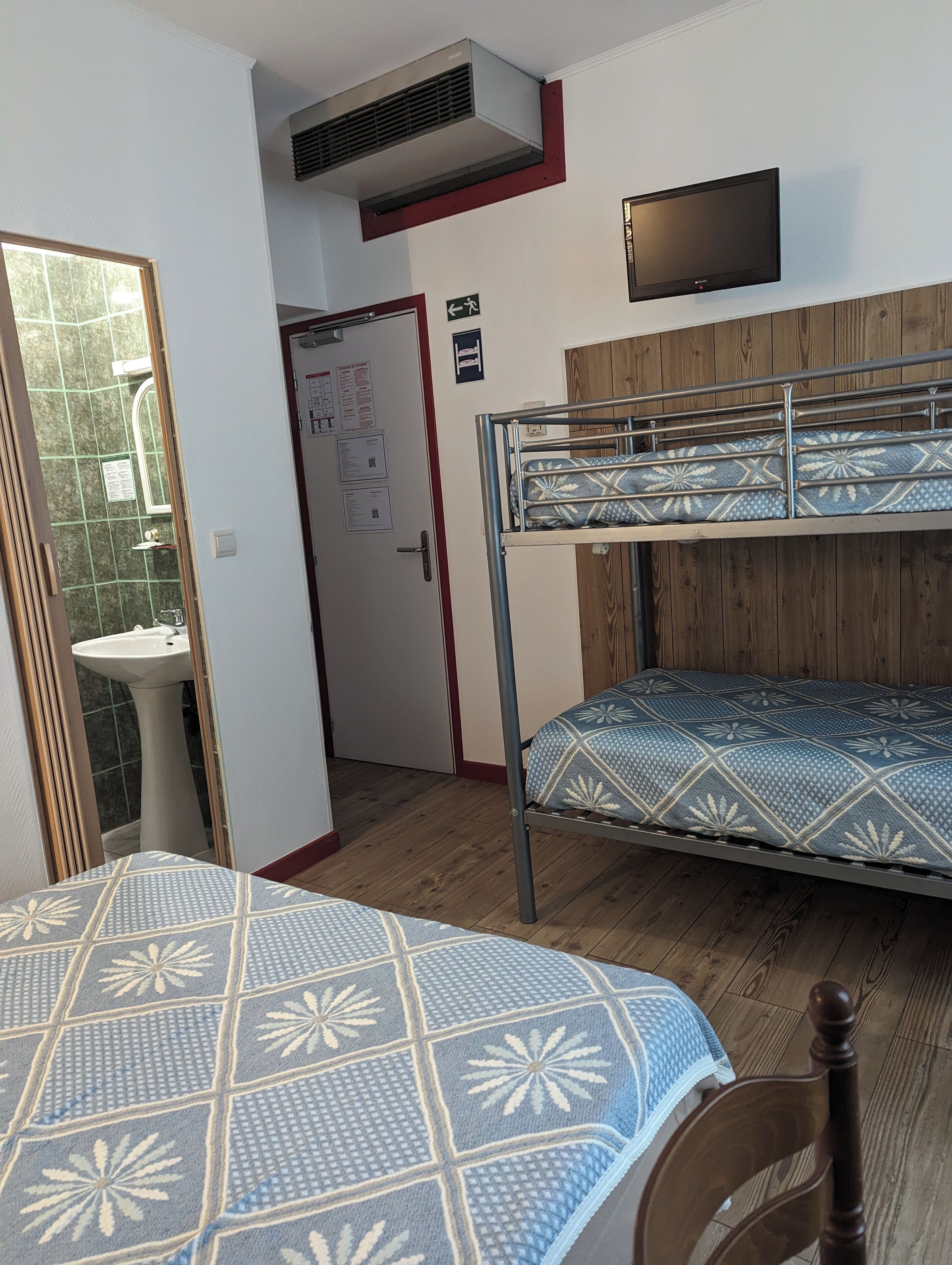 Ein Zimmer mit Etagenbett, Waschbecken, Spiegel und Fernseher an der Wand.