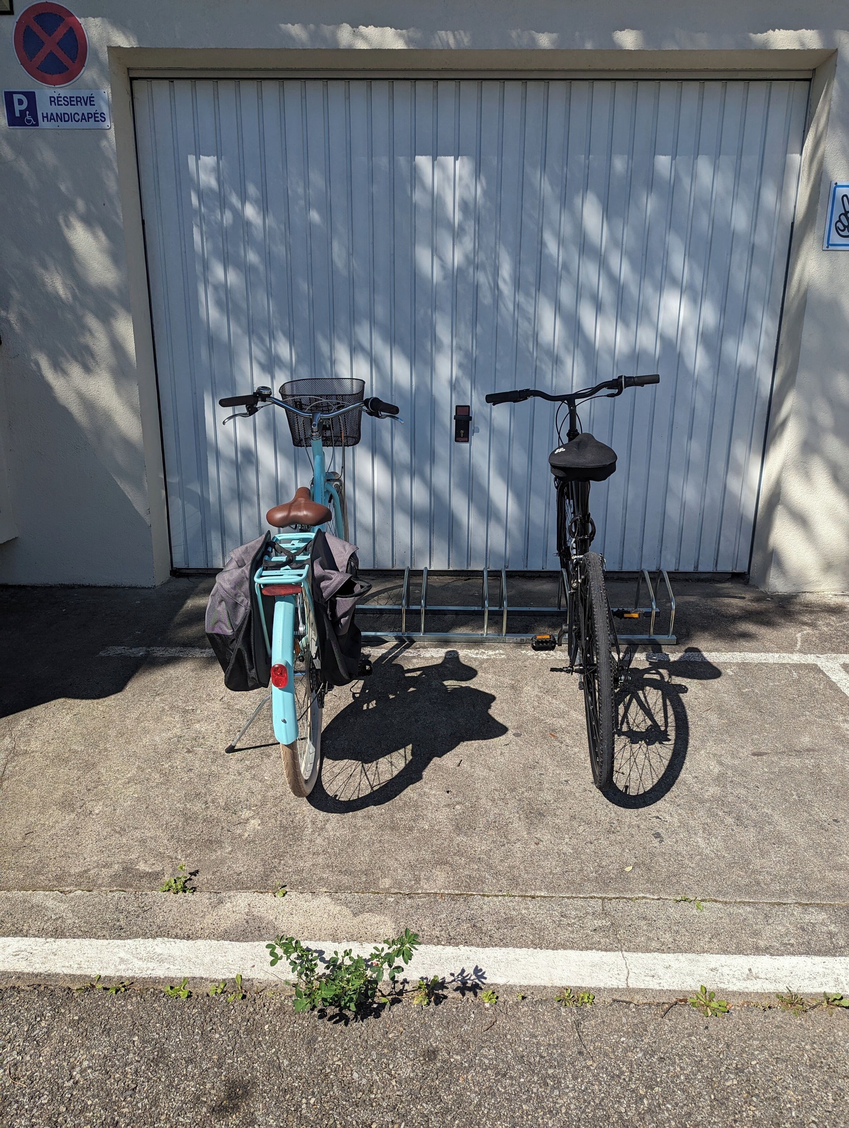 Dos bicicletas estacionadas frente a una puerta de garaje con un letrero que dice 'Reservado para Sillas de Ruedas'.