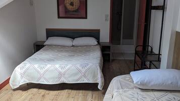 A bedroom with a bed, a small bedside table, a wall-mounted artwork, and a bunk bed with a red door.
