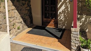A stone building with a red door, a small porch, and a potted plant. - AUBERGE DES PINS (Aubenas)