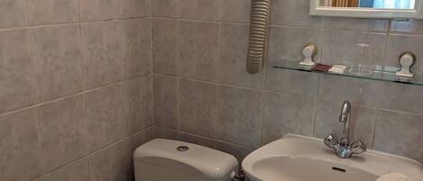 A bathroom with a toilet, sink, and a hairdryer mounted on the wall.