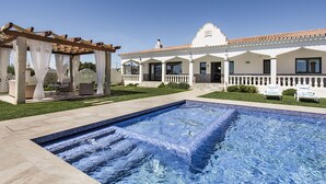 A poolside area with a pergola, outdoor seating, and a swimming pool.