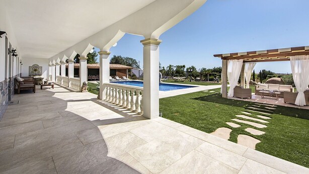 A covered outdoor area with a pool, seating, and a well-maintained lawn.