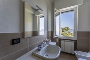 Une salle de bain moderne avec une grande fenêtre, un lavabo, un miroir et des toilettes.