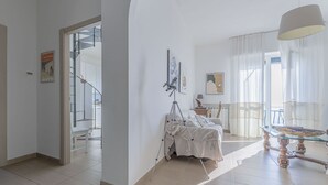Uma sala de estar ampla com escada para um andar superior, um telescópio no chão e uma mesa de jantar com cadeiras.