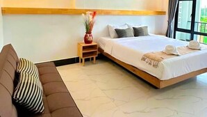 Ein Hotelzimmer mit Bett, Sofa, Nachttisch und Fenster.