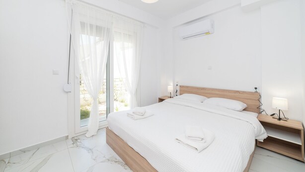 Une chambre à coucher avec un lit, une table de chevet, une lampe et une fenêtre avec des rideaux.