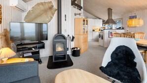 Een moderne woonkamer met een open haard, een televisie en een eethoek.