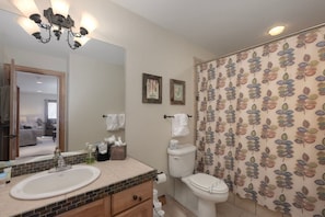 A bathroom with a white sink, a mirror, a chandelier, a toilet, and a shower curtain with a leaf pattern. - Luxe MTN Escape 15 min to Winter Park Base (Tabernash)
