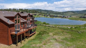 A wooden cabin with a balcony overlooking a lake and hills.