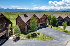 A residential area with multiple houses, a driveway, and a mountainous landscape in the background. - Luxe MTN Escape 15 min to Winter Park Base (Tabernash)