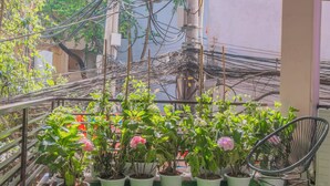 Varanda com grama sintética, plantas em vasos e uma cadeira.
