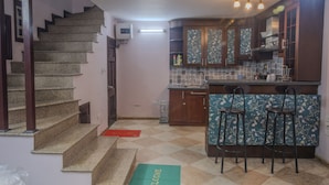 Cozinha com escada, banquetas e tapete de boas-vindas.