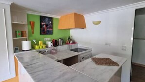 A compact kitchen with a marble countertop, a built-in oven, and a green accent wall. - Oasis on the Montgo, cozy apartment with large covered terrace (Dénia)